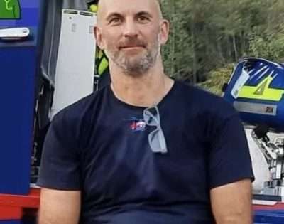 David Dungay, bald man with beard wearing navy blue t shirt with glasses tucked into collar